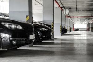Indoor parking garage with multiple black cars parked in reserved bays.