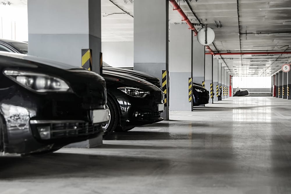Indoor parking garage with multiple black cars parked in reserved bays.